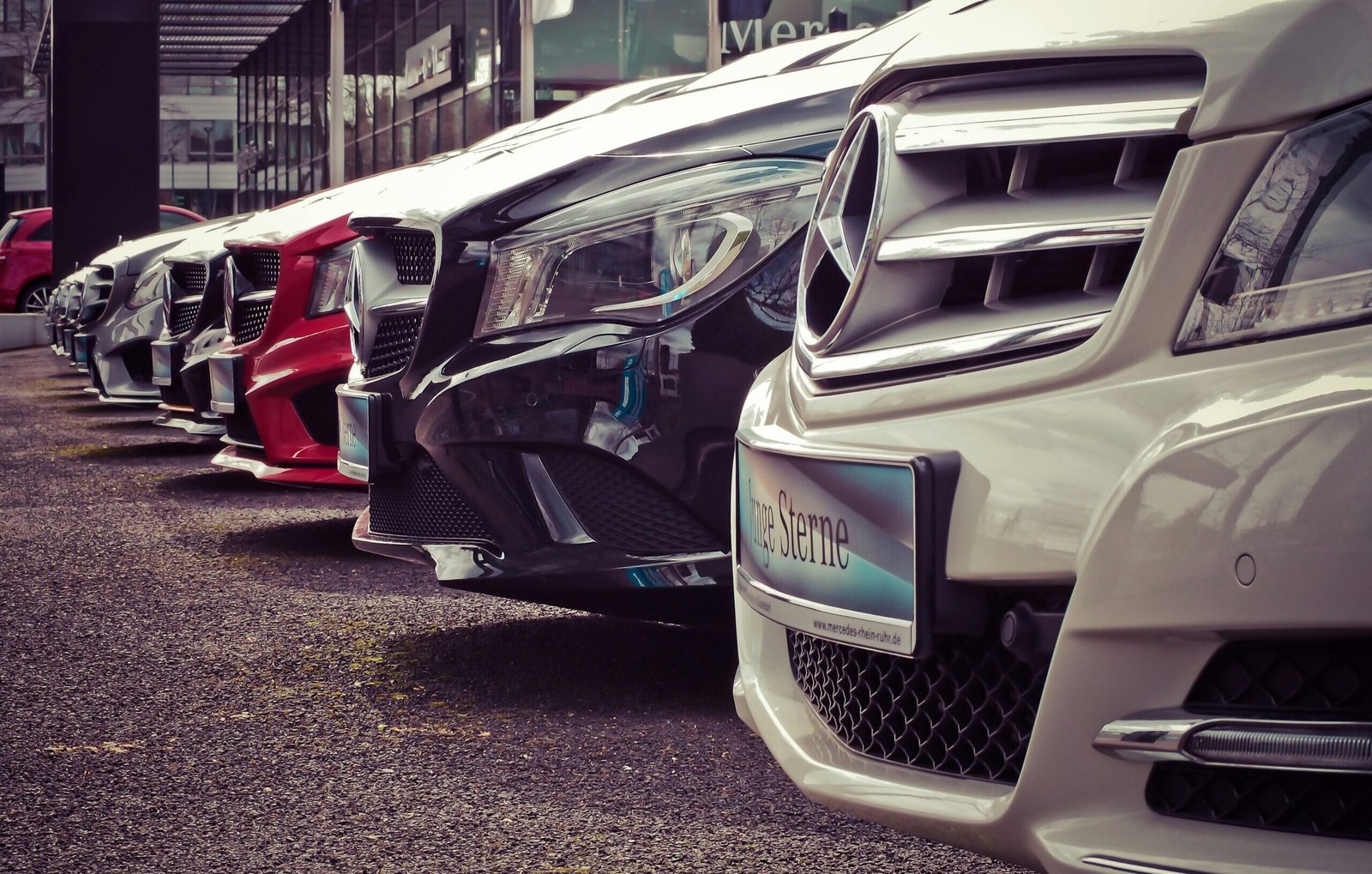 Luxury cars lined up at an outdoor dealership, showcasing sleek designs.